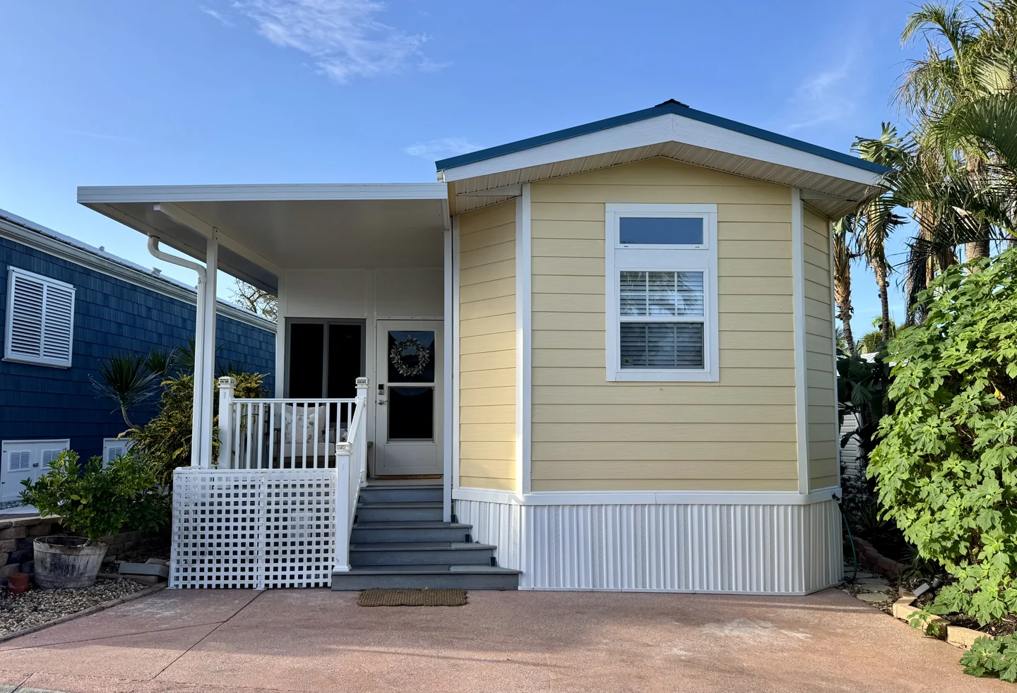 Stella’s Sol Shack, a sunny yellow home with a white front porch and tropical landscaping